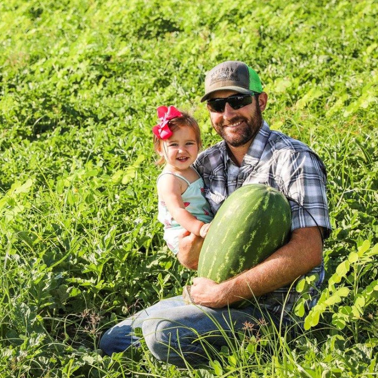 a farmer and his daughter holding a watermelon